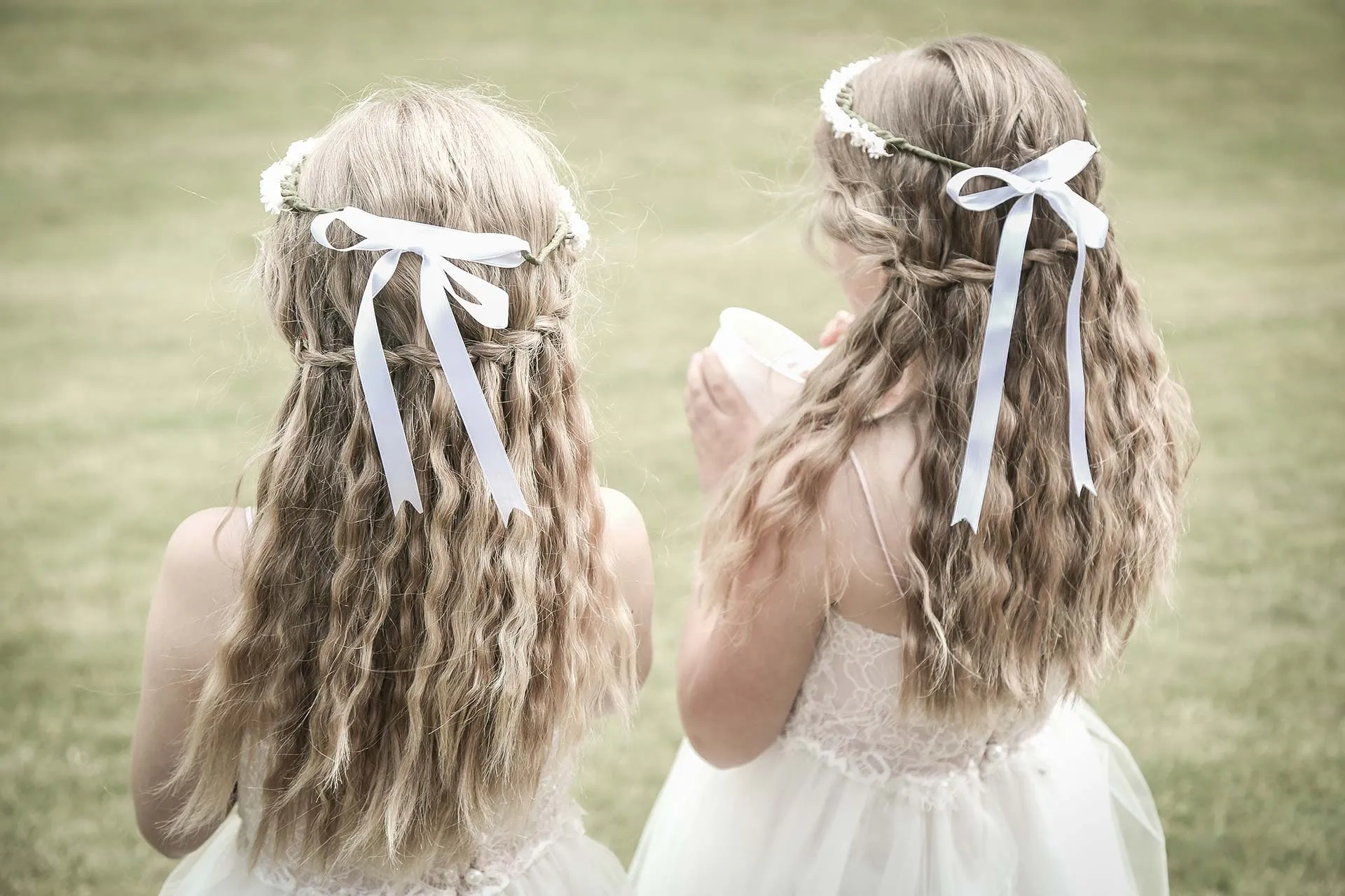 Two young flower girls with white ribbons in their hair