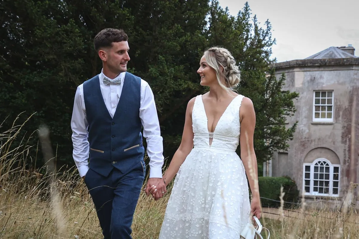 Newlyweds walking hand in hand through the Pennard House grounds