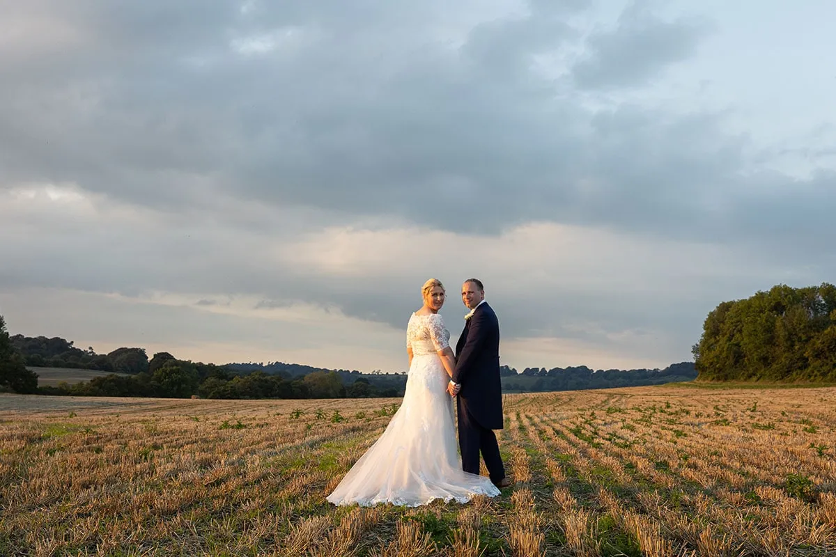 Newlyweds in a Somerset field under a dramatic sky