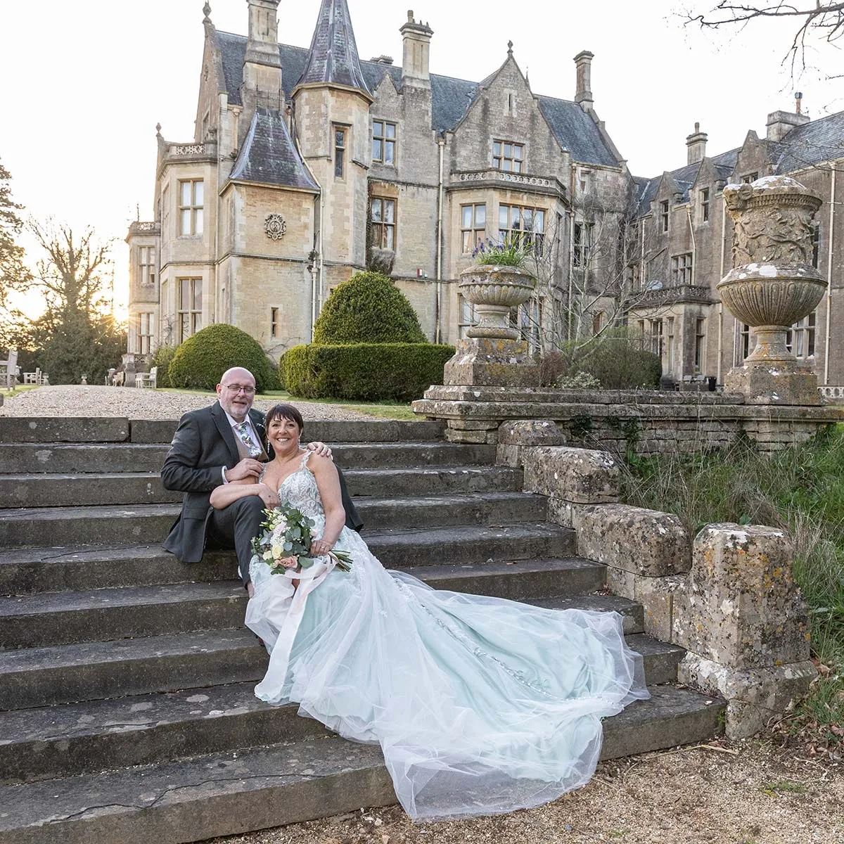 Bride's dress trailing down the steps of a manor house