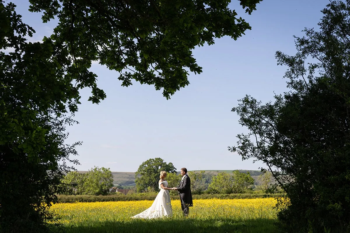 Couple photographed beside a rapeseed field on their wedding day