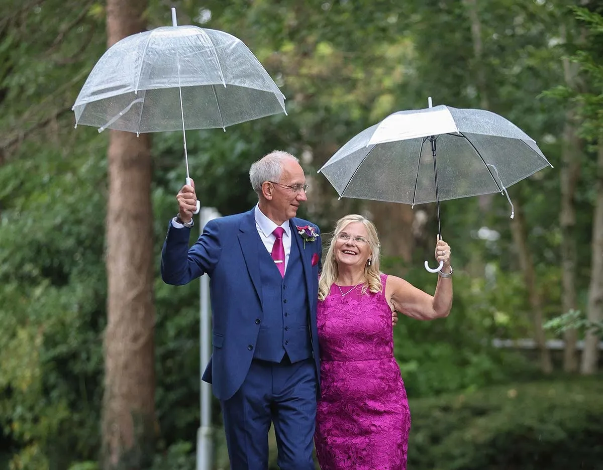 Couple under clear umbrellas on a rainy wedding day