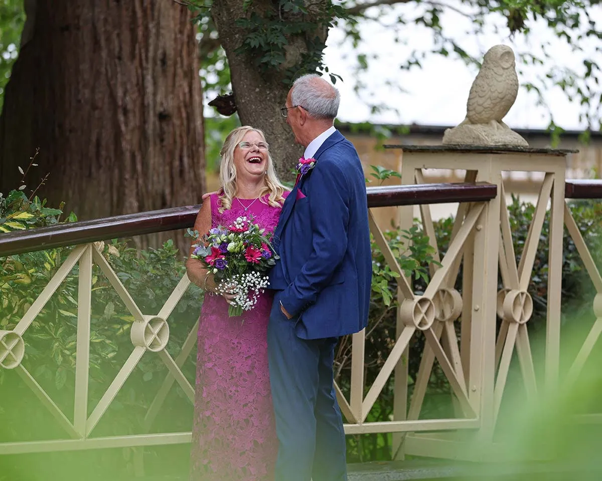 Bride and groom photographed on a bridge in the venue gardens
