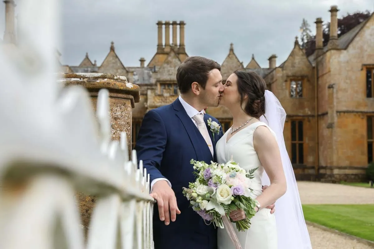 Bride and groom sharing a kiss outside their manor house venue