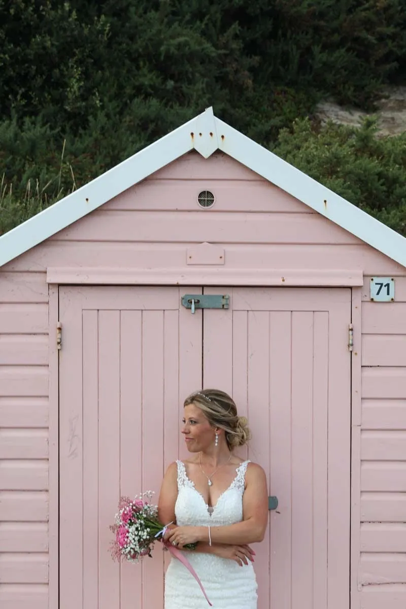 Bride beside a pink beach hut on the Dorset coast